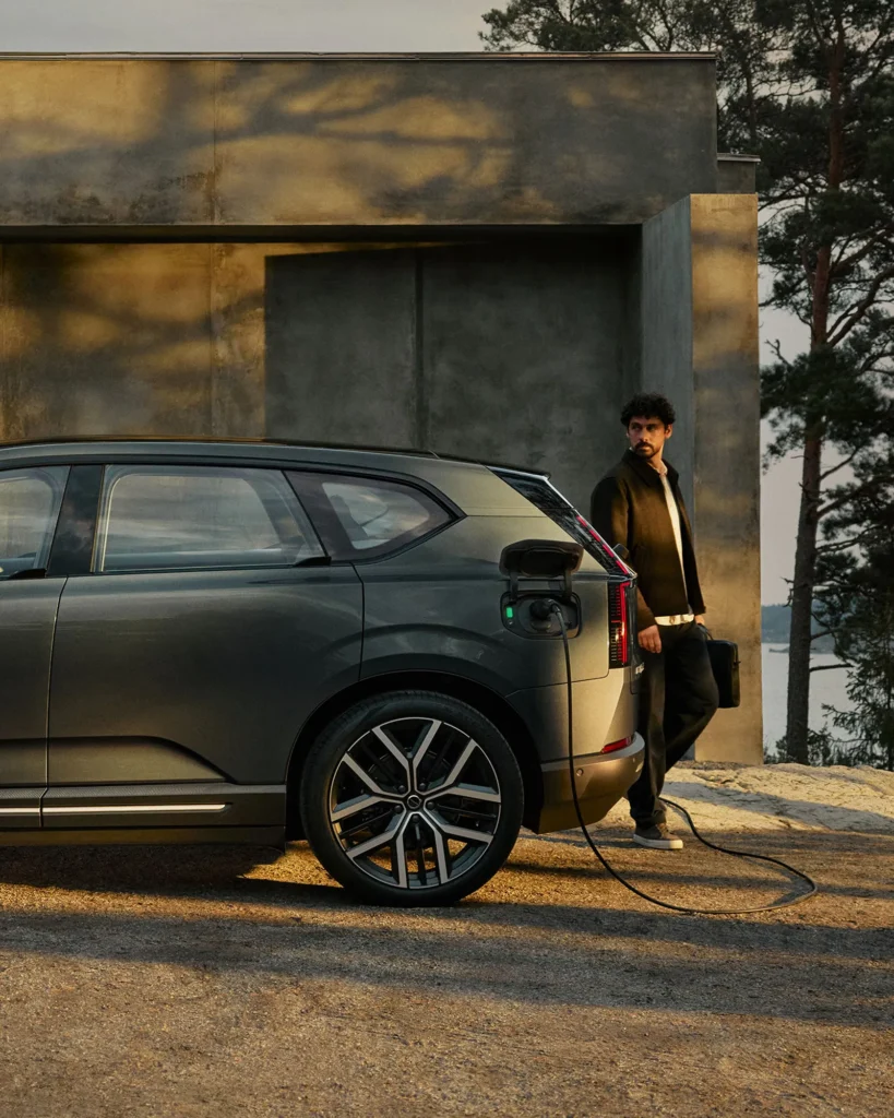 Volvo EX60 mögött egy férfi áll miközben az autó töltőn van